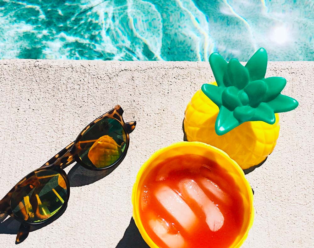 sunglasses with drink by the pool