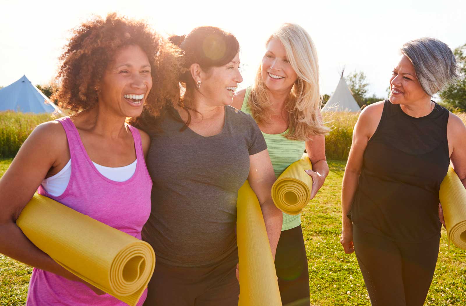 four women with yoga mats laughing