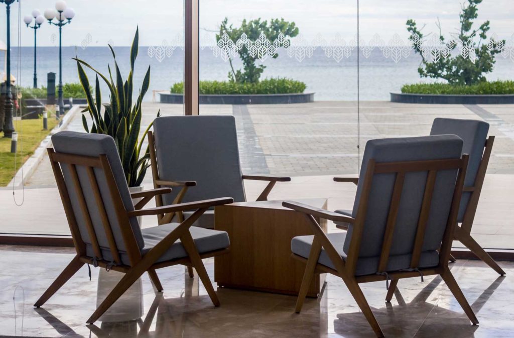 four chairs in lobby of hotel overlooking water