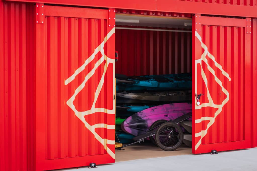 Red shipping container with kayaks stacked up on the inside. 