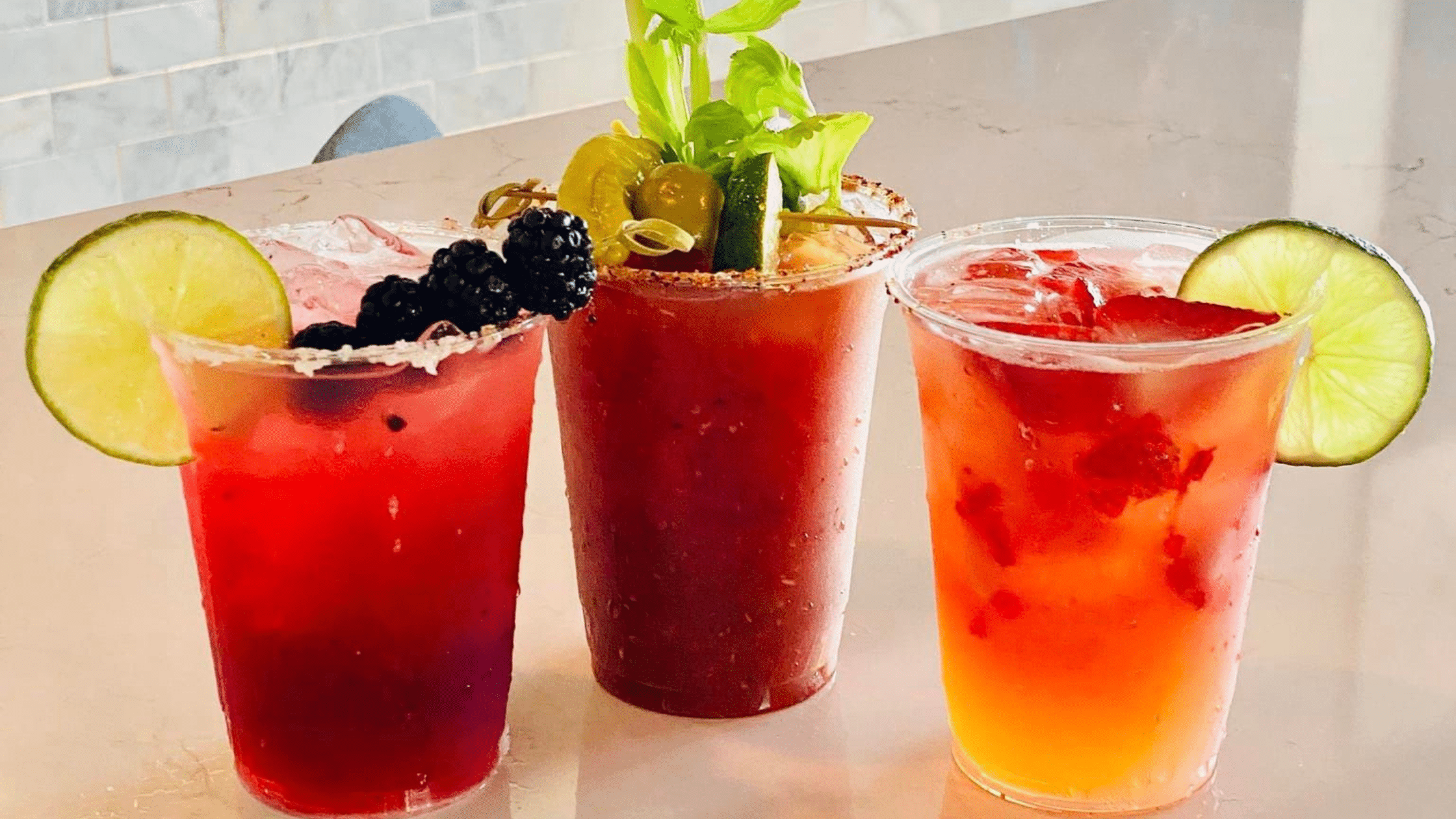 Three red and orange drinks with garnishes