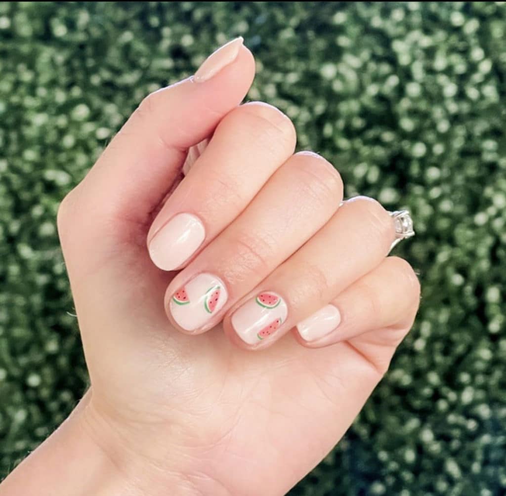 Person showing off light pink/nude nails with watermelons painted on top