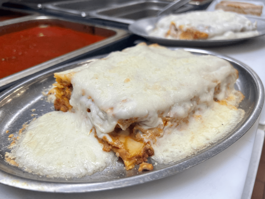 Lasagna covered in cheese on silver platter