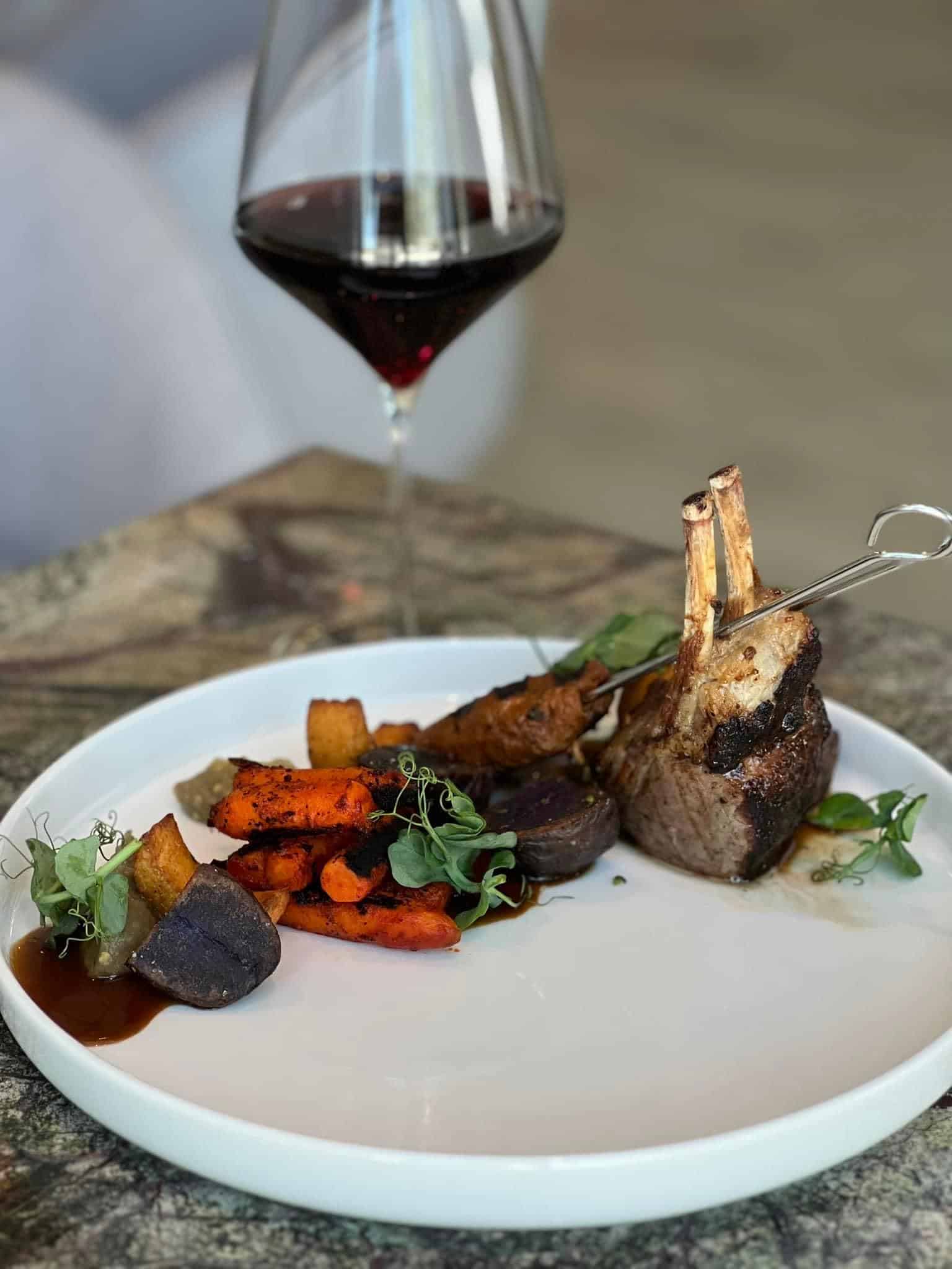A plate of lamb, carrots and decorational herbs