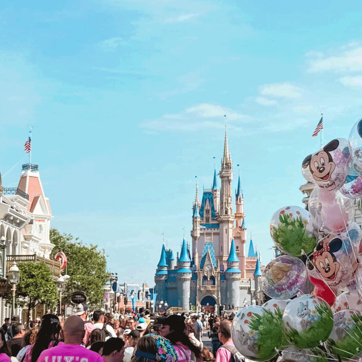An image of Disney World taken from the busy main street with a view of the Disney castle over the crowd in the far distance.