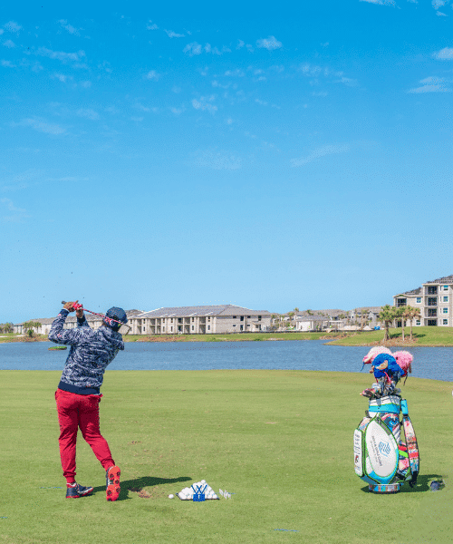 A golfer swinging into the distance next to the waterfront