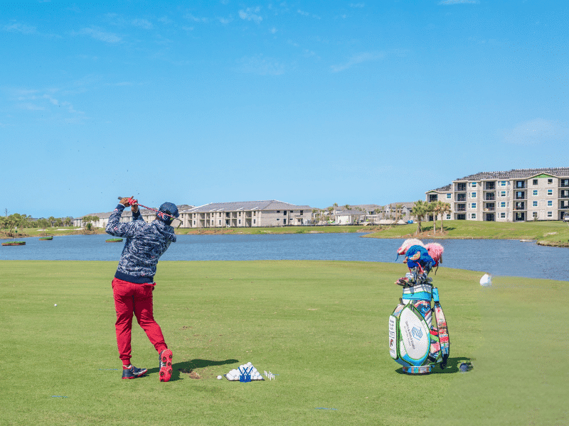 A golfer swinging into the distance next to the waterfront