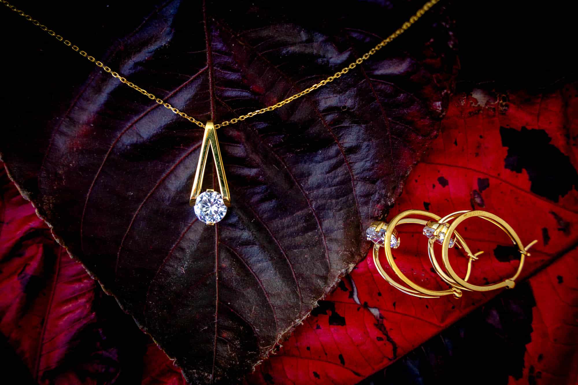 A necklace on display on a leaf, with matching earings next to the leaf