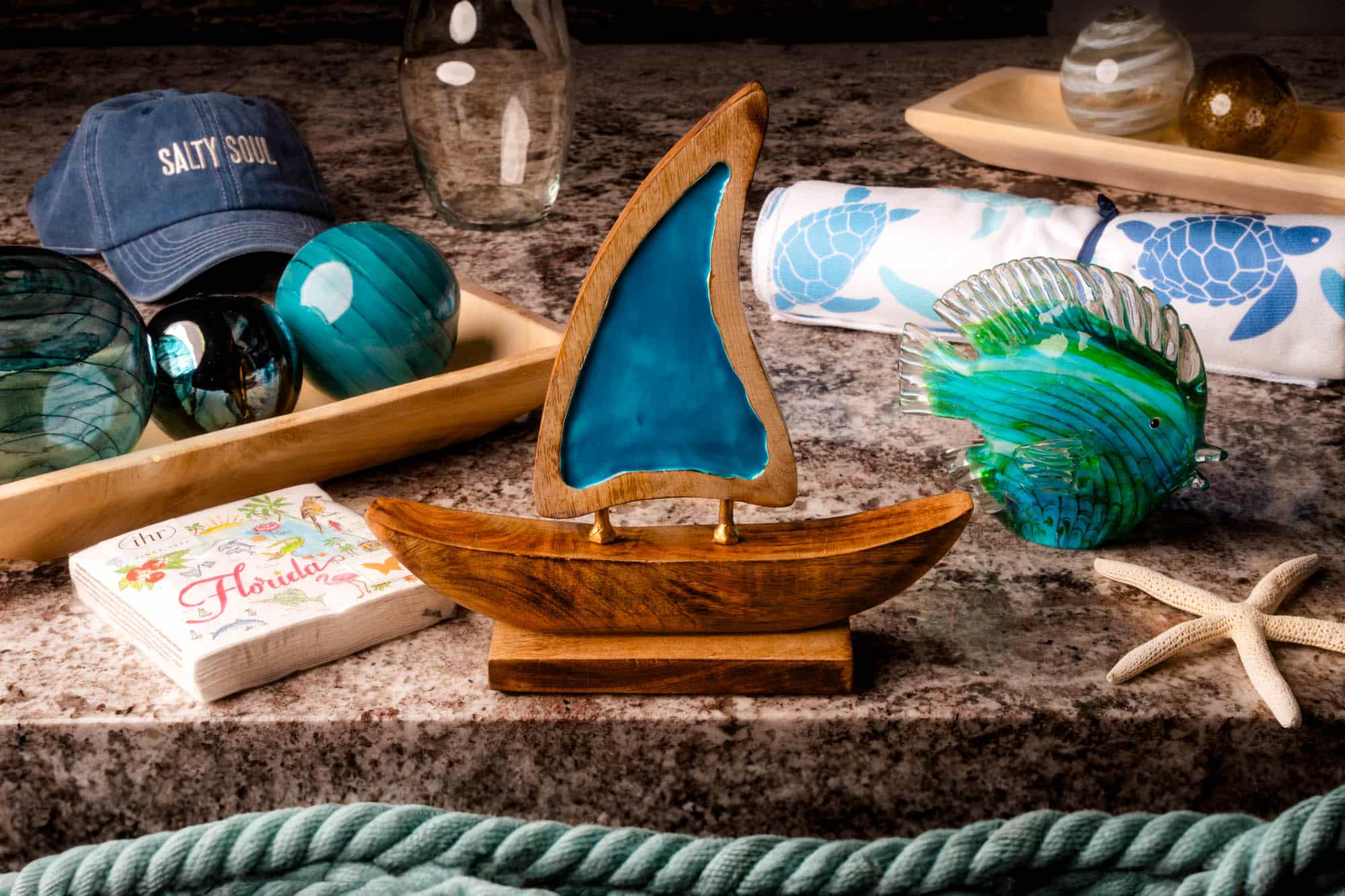 A display of a wooden toy board with a blue sail, a starfish, and decorative balls the color of the ocean
