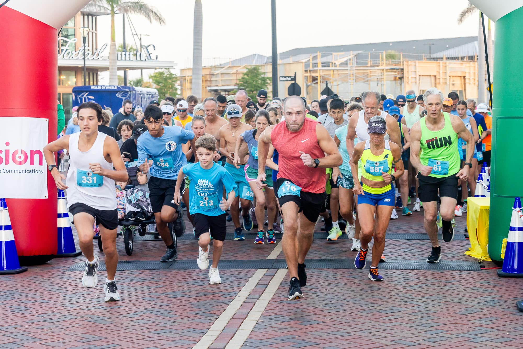 A group of people at Downtown Wellen Park at the archway - starting their race.