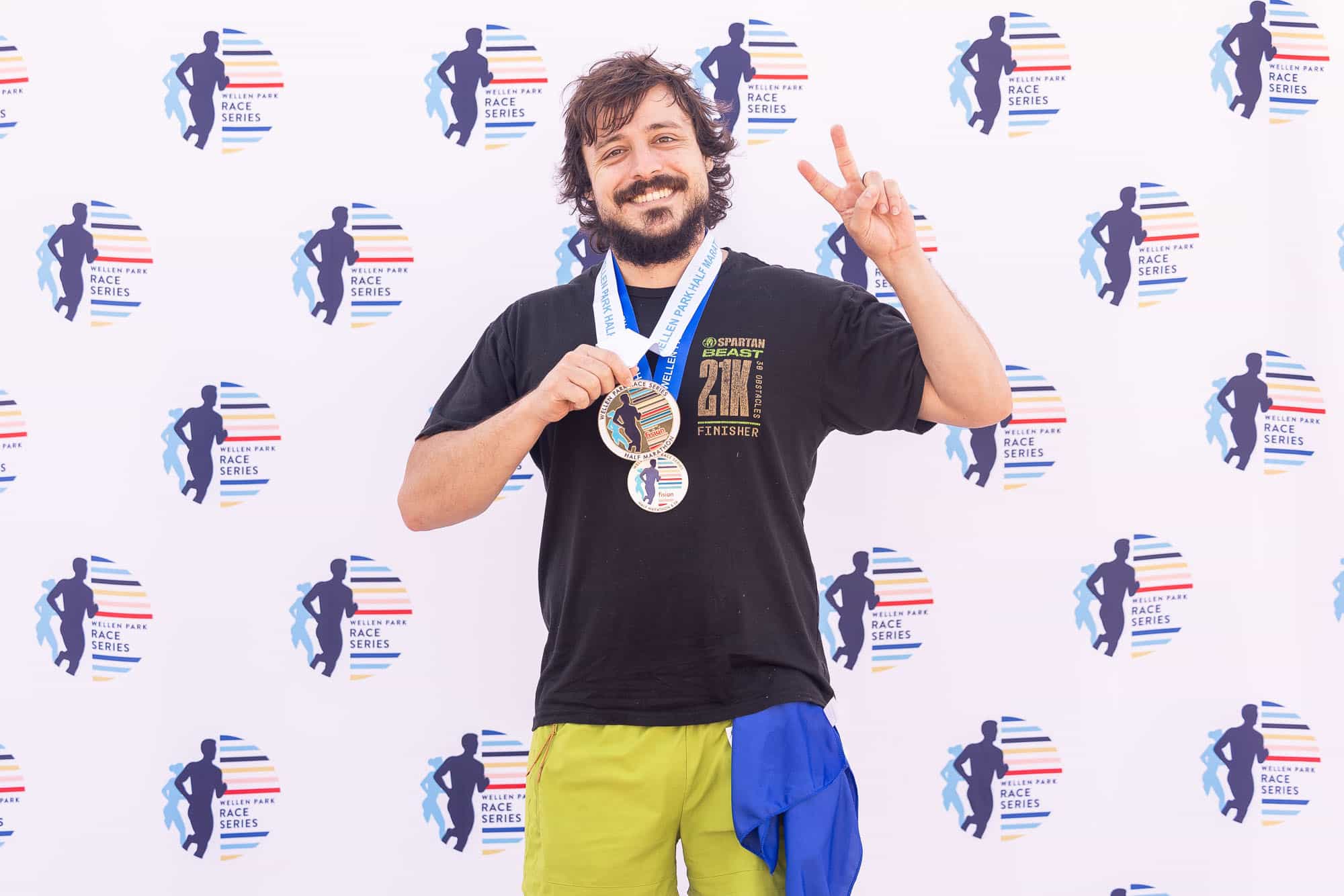 The winner of the Wellen Park Half Marathon standing with two medals on their neck, while holding up the peace sign