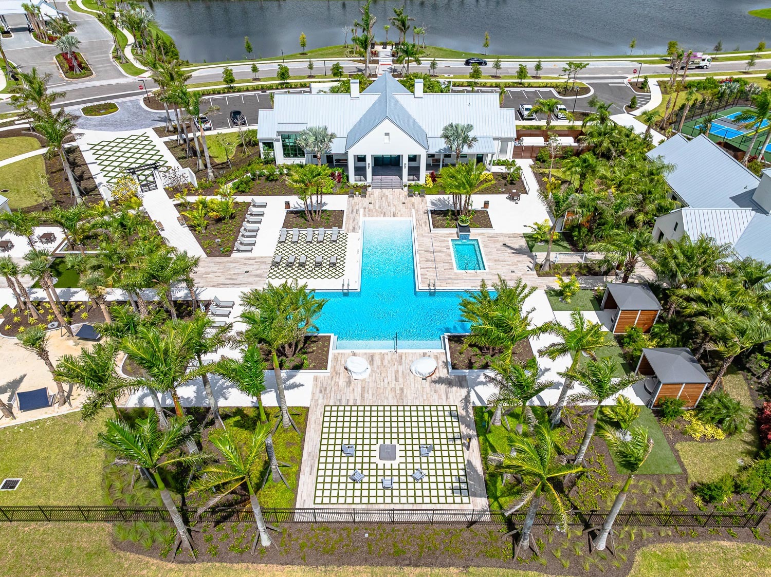 An aerial view of the Everly at Wellen pool amenitiey with a fire pit, cabanas, a pool house, lounge chairs, hamocks with tennis courts off to the side