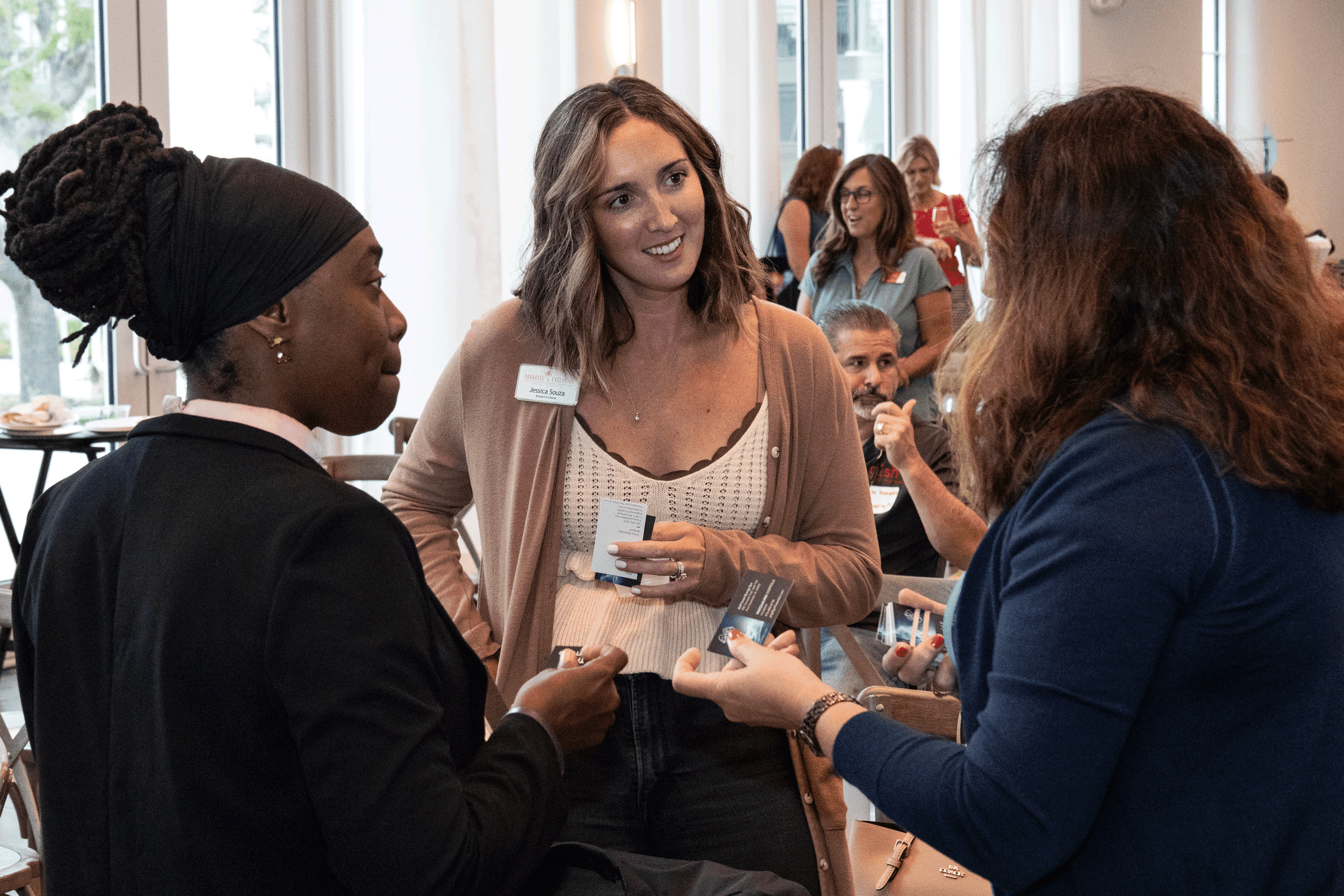 Guests exchanging business cards and chatting during a professional networking event inside a bright, modern venue