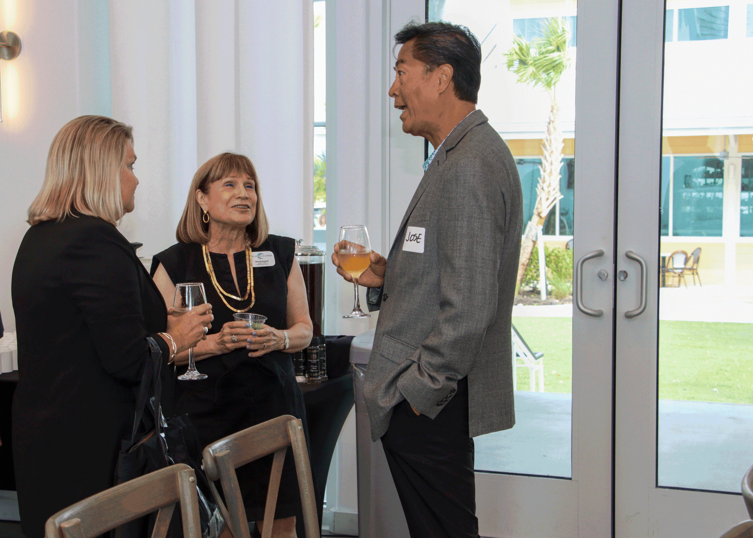 Professionals chatting over drinks during a networking event inside a bright, modern venue.