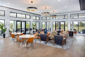 A lounge with dining tables and high tables at the Sunstone Lakeside residential community at Wellen Park