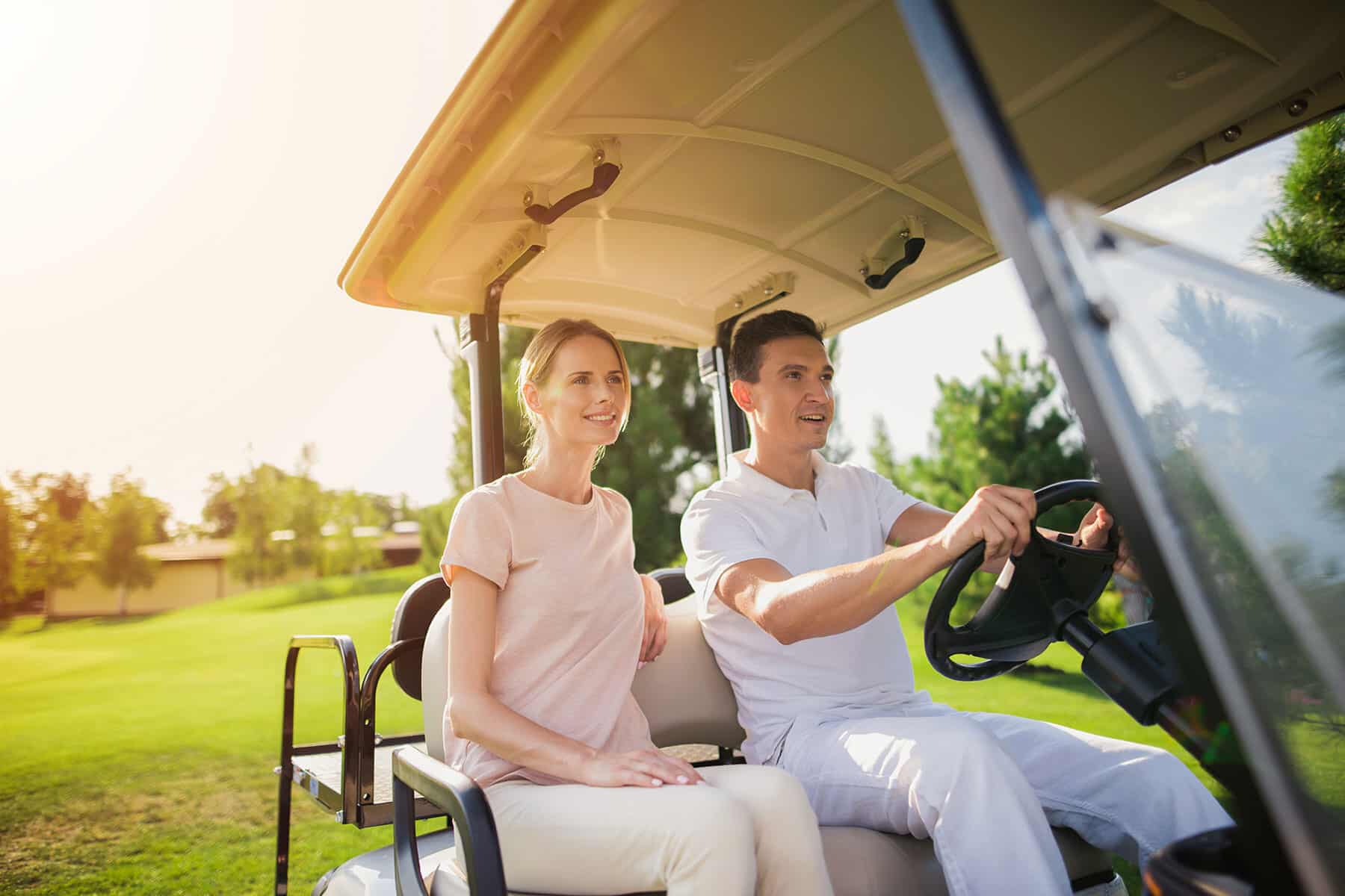 A stock couple riding a colf cart on a golf course at Sunstone Lakeside community