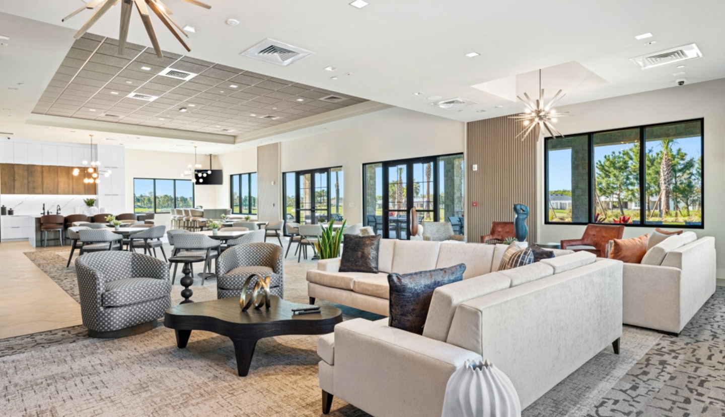 A lounge venue with a kitchen area and large windows at the Esplanade community at Wellen Park