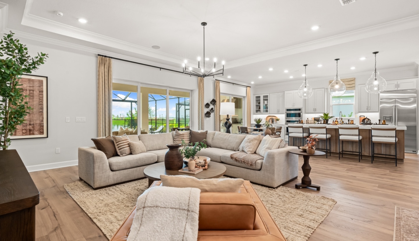 An open plan living room with a living room area and a kitchen with a large kitchen island at the Esplanade community at Wellen Park