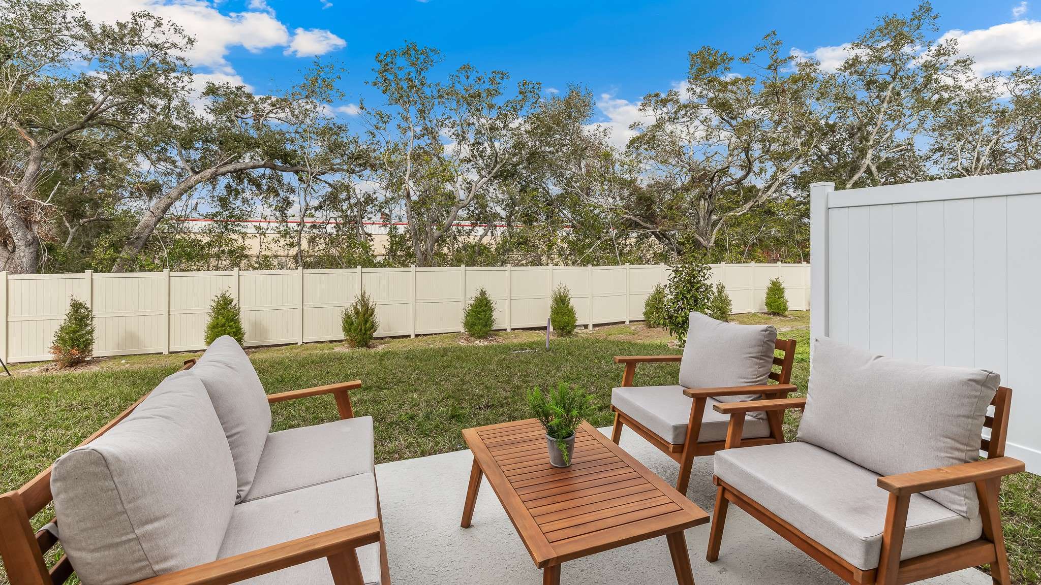 Private backyard patio with outdoor seating, a fenced yard, and landscaped greenery, offering a quiet and comfortable outdoor retreat.
