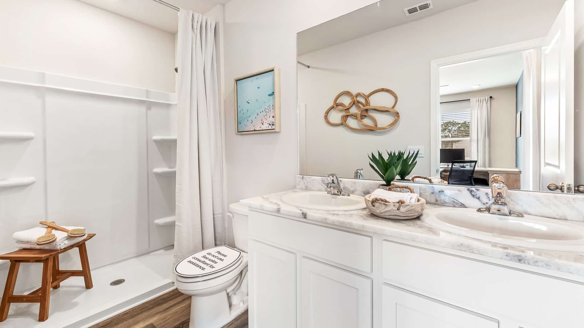 Bright bathroom with a double vanity, marble-look countertop, and a walk-in shower, featuring clean finishes and modern decor.