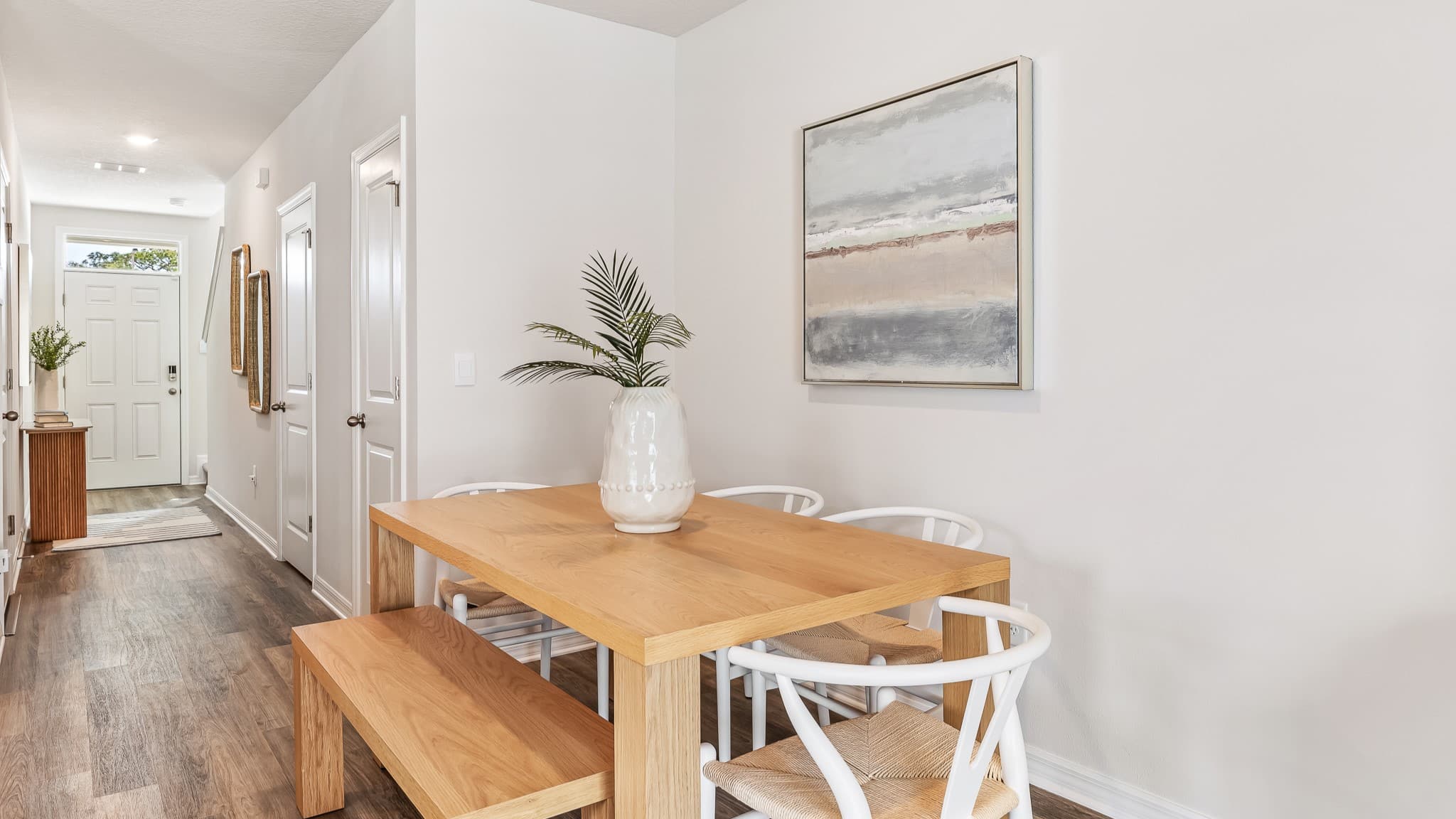 Minimalist dining area with a wood table, bench seating, and modern chairs, styled with neutral decor and clean finishes.