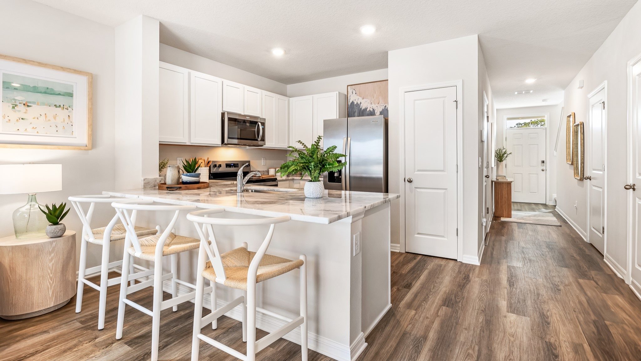 Open-concept kitchen and dining area with white cabinetry, a breakfast bar with seating, and modern finishes throughout.
