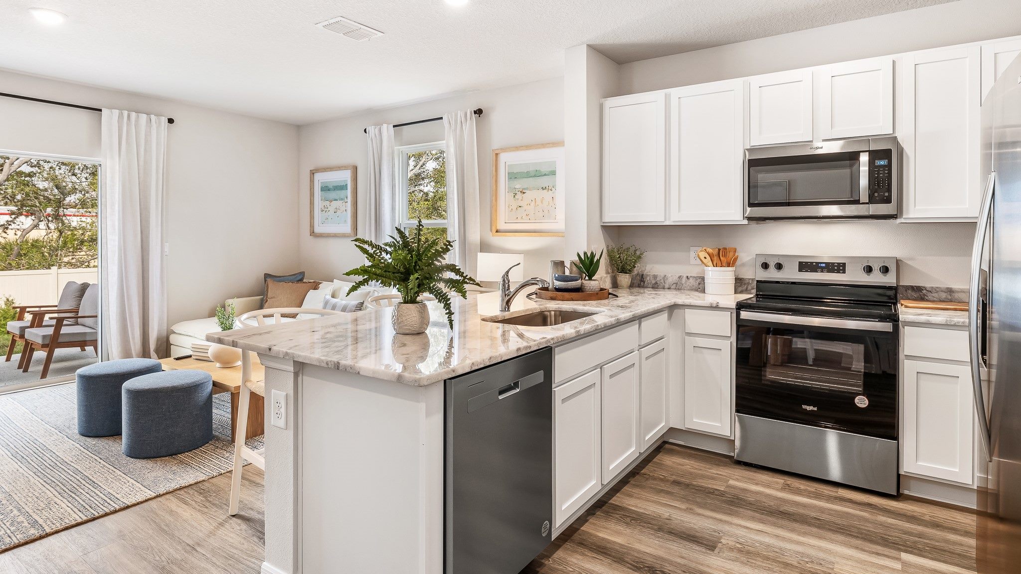 Bright, modern kitchen with white cabinetry, stainless steel appliances, and a spacious island that flows seamlessly into the open-concept living area.